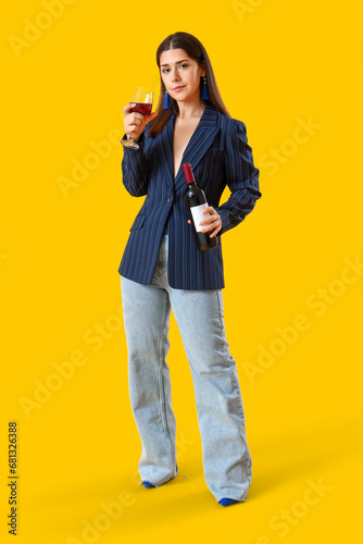 Young woman with glass of wine on yellow background