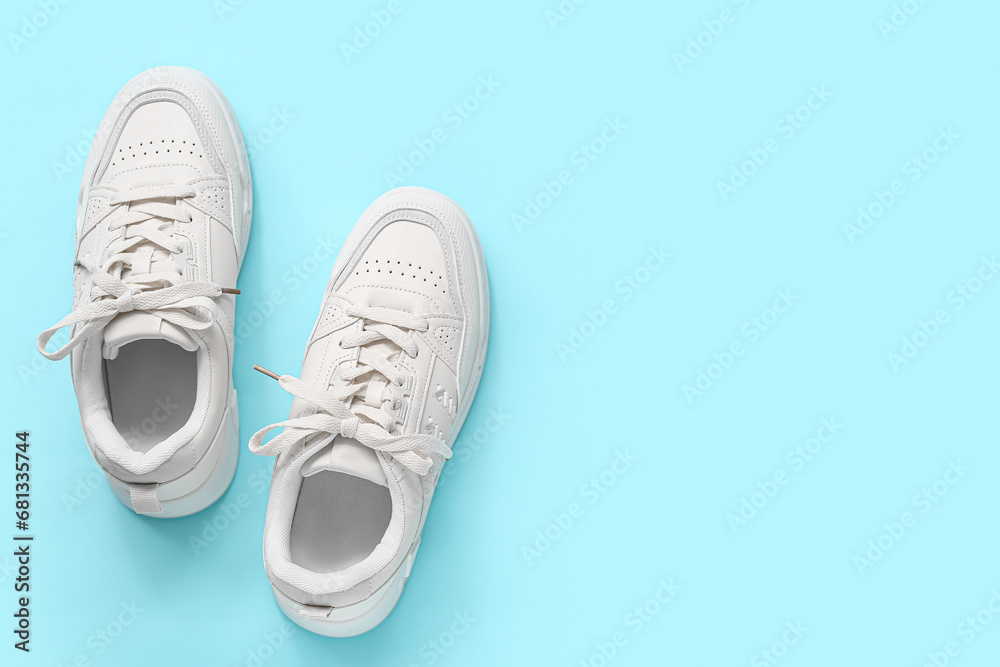 Stylish white sneakers on blue background Stylish white sneakers on blue background