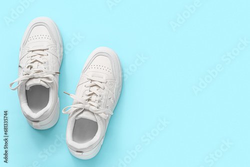 Stylish white sneakers on blue background