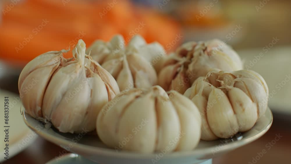 Garlic lies on a plate. Large juicy garlic in the skin is ready as an ingredient for Uzbek pilaf. The smell of garlic wafts through the room. The garlic heads are ready for cooking Garlic lies on a plate. Large juicy garlic in the skin is ready as an ingredient for Uzbek pilaf. The smell of garlic wafts through the room. The garlic heads are ready for cooking