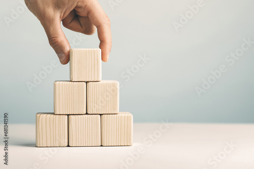 Hand putting and stacking blank wooden cubes on table with copy space for input wording or infographic icon