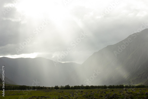 Sun shines through the clouds in mountains, sun rays from the sky