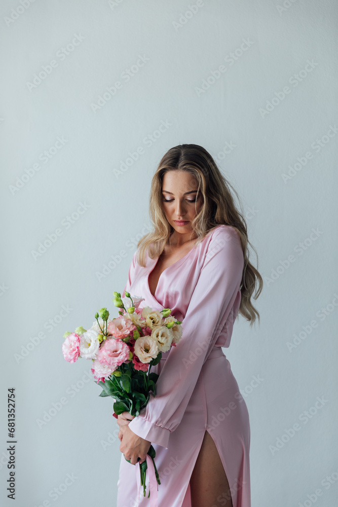 a woman in a pink dress with flowers stands in a bright room