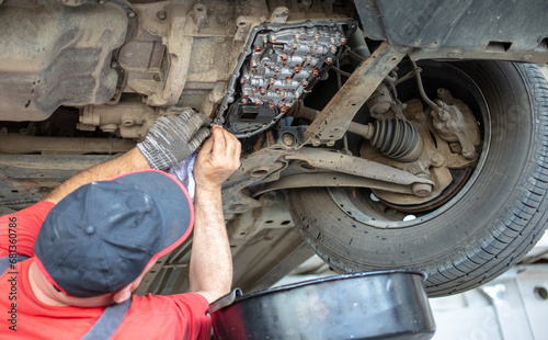 A mechanic at a car service center disassembles a CVT on a car photo