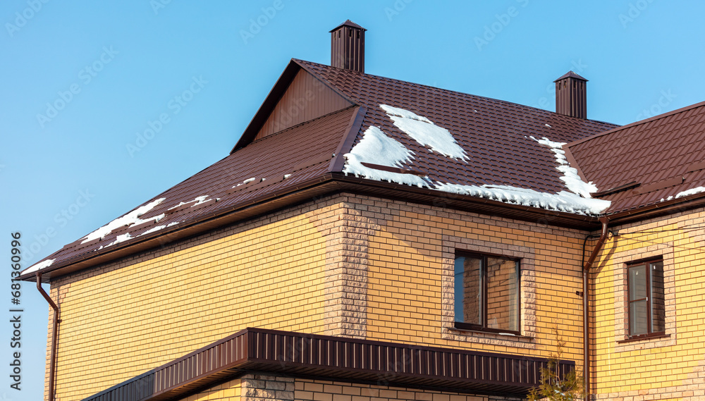 Roof of a house covered in snow against a blue sky