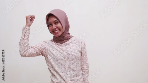 Young asian muslim girl celebrating her victory with fist or cleched hands. Isolated on white bakground photo