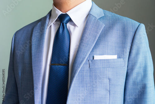 ฺBlue necktie in half winsor knot with single dimple and tie clip pairing with hidden button collar shirt and light blue blazer and white pocket square folded in presidential style. photo