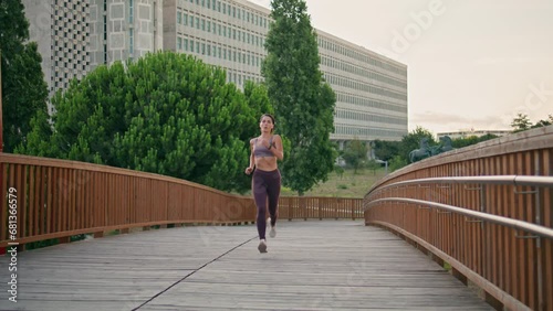 Active jogger running urban park. Satisfied athletic woman doing cardio training photo