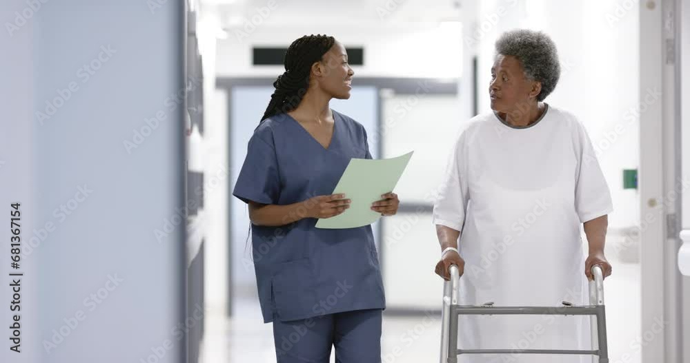 African american female doctor and senior woman with crunches walking in hospital, slow motion