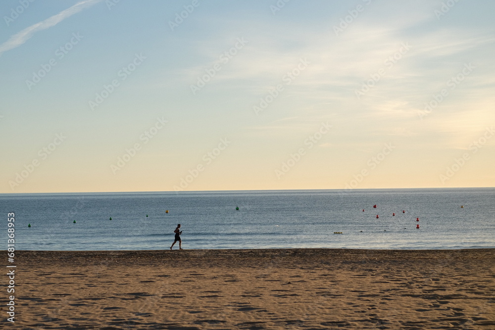 an athlete jogging along the seashore against the backdrop of sunrise on a bright sunny day in Spain
