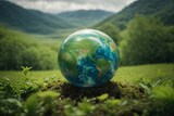 Globe in the green grass with mountain background. Earth day concept.