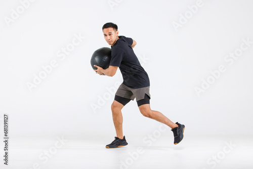 Isolated cutout full body studio shot strong Asian male fitness athlete sportman trainer model in black casual sport workout outfit posing holding lifting exercise ball training on white background