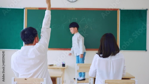 Asian adorable son draw picture on blackboard in classroom with parent.  photo