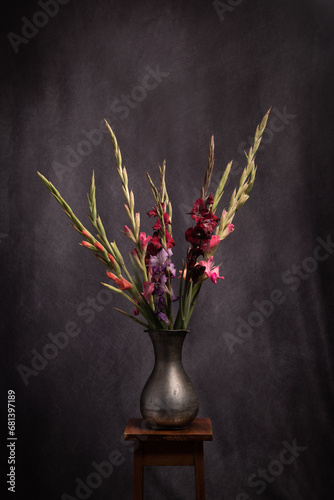 still life with gladiolus flowers in a vase in dark painterly renaissance style photo