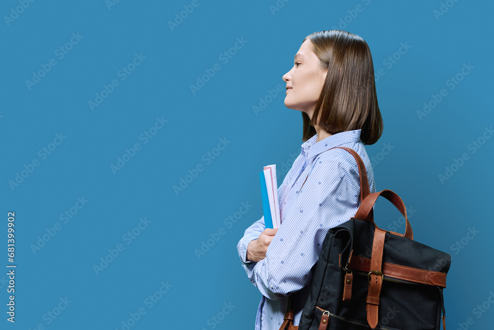Profile view of young woman college student on blue background Profile view of young woman college student on blue background