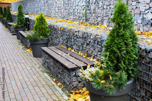 gabion retaining walls. wooden benches built into a dry wall in the park photo
