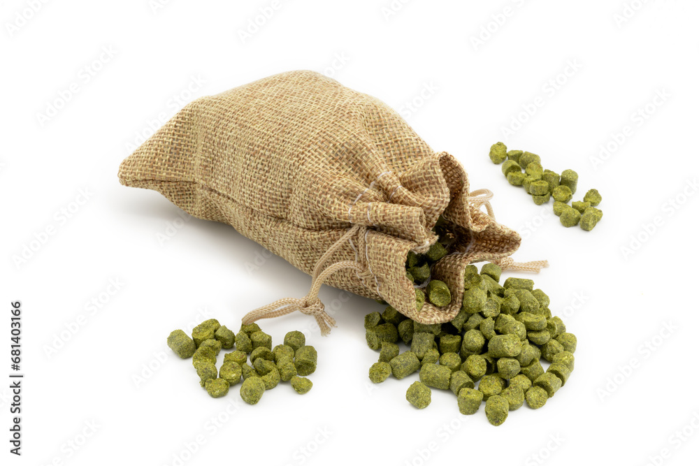 Small jute bag with pile of green hops pellets on white background.