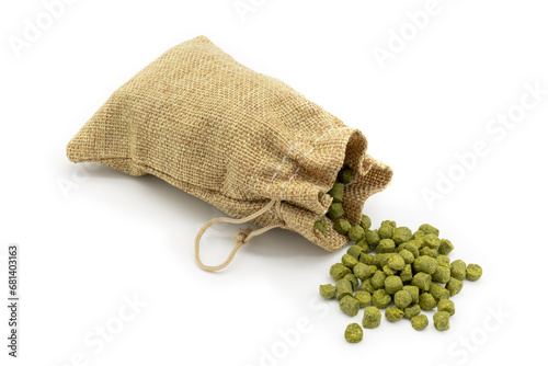 Small jute bag with pile of green hops pellets on white background.