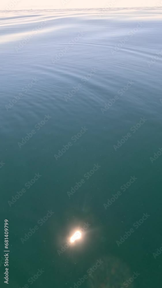 Vertical aerial view on sea water surface, camera flies over clear sea water. Sun glare. Abstract nautical summer ocean nature. Holiday, vacation and travel concept. Nobody. Weather and climate change Vertical aerial view on sea water surface, camera flies over clear sea water. Sun glare. Abstract nautical summer ocean nature. Holiday, vacation and travel concept. Nobody. Weather and climate change