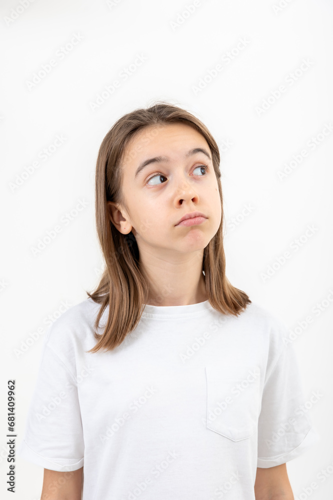A teenage girl grimaces with displeasure on a white background, isolated. A teenage girl grimaces with displeasure on a white background, isolated.