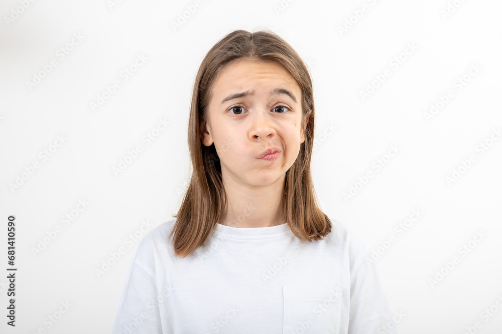A teenage girl grimaces with displeasure on a white background, isolated. A teenage girl grimaces with displeasure on a white background, isolated.
