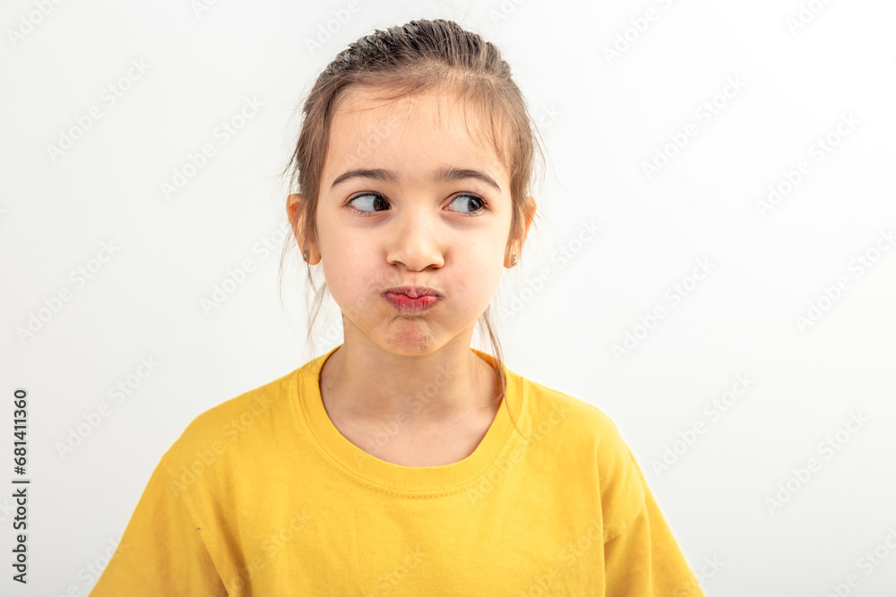 Little Caucasian girl makes funny faces on a white background isolated. Little Caucasian girl makes funny faces on a white background isolated.