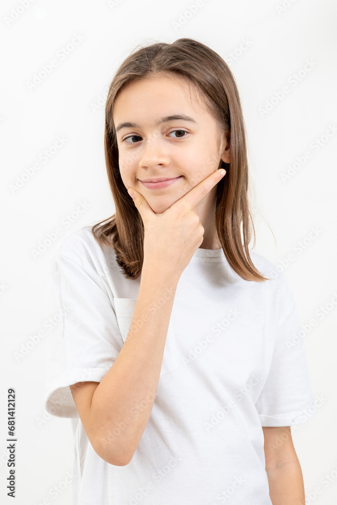 A schoolgirl thoughtfully holds her hand near her face on a white background. A schoolgirl thoughtfully holds her hand near her face on a white background.