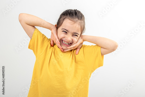 Portrait little girl keeping hands near face, smiling isolated on white.