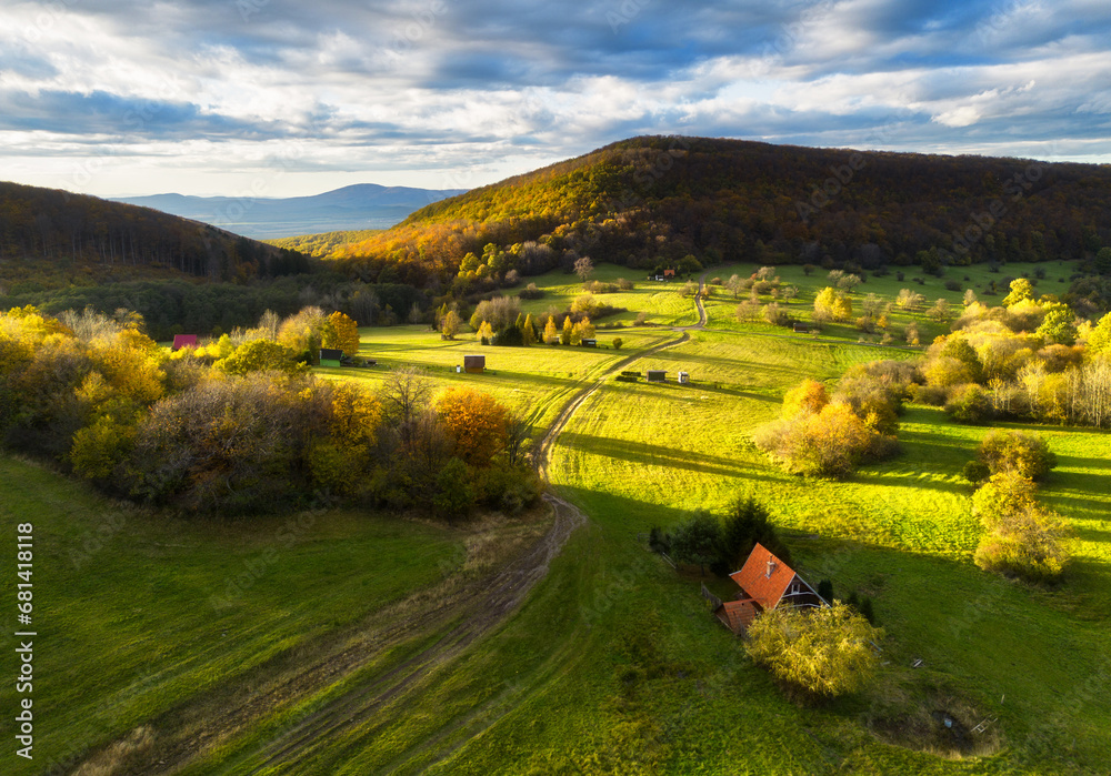 Aerial view in summer in Slovakia. Ggreen meadows and fields, grass and trees, rural road at dawn in spring. Top drone view of mountain countryside