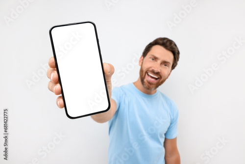 Handsome man showing smartphone in hand on white background, selective focus. Mockup for design