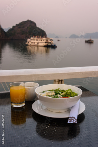 Early morning breakfast consisting of orange juice, coffee and a bowl of chicken and ric noodle soup onboard a luxury cruise ship on Halong Bay
