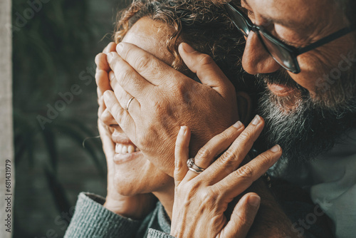 Couple at home in romance leisure activity. Man covering eyes to woman making a surprise. People in love and relationship indoor. Happy lady with husband enjoying a new day. Serene married people photo