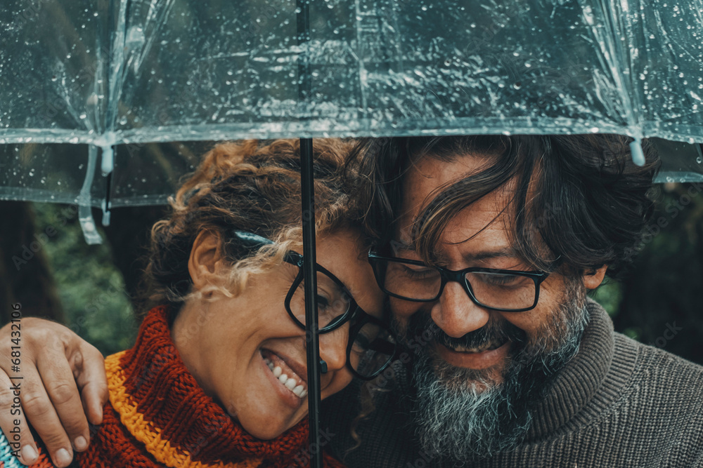 Romantic couple in love under umbrella in rainy day. Man and woman enjoy relationship and happiness together in winter autumn rain. Romance and people smiling end hugging at the park in leisure moment