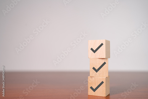 Check mark icons on wooden stacked blocks. Task lists, Checklist, Survey, Assessment, List, Confirm items, Double check, Quality Control. Goals achievement business success. © apiwat