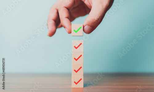 Checklist, Task list, Survey and assessment. Quality Control. Goals achievement and business success. Hand holding Check mark on wooden blocks for complete check list.