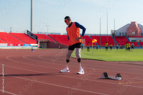 Disabled athletic man stretching and warming up before running on stadium track