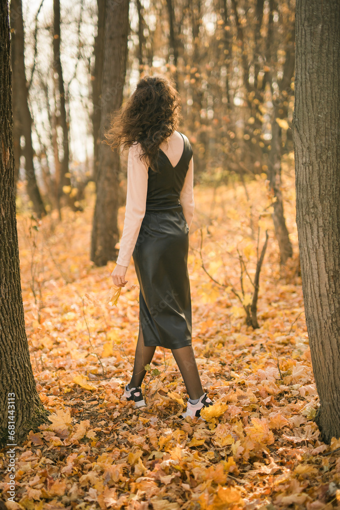 Attractive young woman walking in autumn park, happy mood and fashion style trend and curly long brown hair. Fall season and pretty female portrait copy space. Millennial generation concept Attractive young woman walking in autumn park, happy mood and fashion style trend and curly long brown hair. Fall season and pretty female portrait copy space. Millennial generation concept