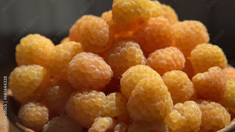 Yellow raspberries in a wooden bowl on the table. Summer berries background. Vitamin food, berry harvest. Healthy nutrition. Yellow raspberries in a wooden bowl on the table. Summer berries background. Vitamin food, berry harvest. Healthy nutrition.