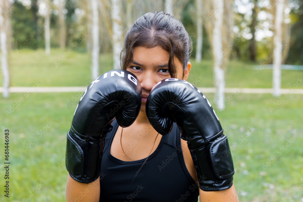 Hispanic female boxer portrait training wearing boxing gloves in a guard position. Fighting sport outdoors workout. Hispanic female boxer portrait training wearing boxing gloves in a guard position. Fighting sport outdoors workout.