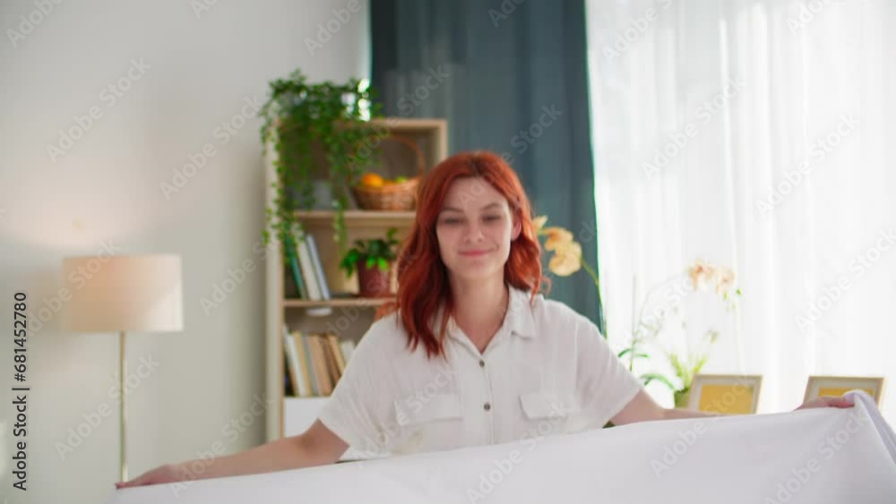 portrait of beautiful young housewife cleaning room and making bed with white linens, smiling and looking at camera portrait of beautiful young housewife cleaning room and making bed with white linens, smiling and looking at camera