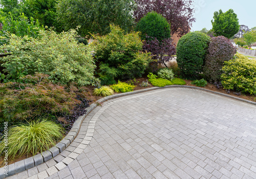 Stylish block paving drive with beautiful garden border with shrubs and flowers. photo