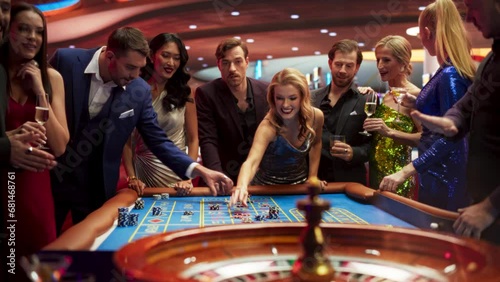 Gathering of Wealthy Young Individuals, Standing Together Around a Roulette Table in a Contemporary Casino Setting. Cinematic Nightlife Footage, Carefree Gamblers Congratulating the Winning Players photo