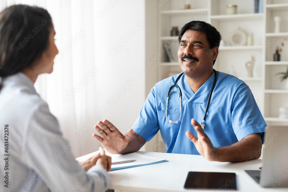 Indian Male Doctor In Blue Uniform Consulting Young Female Patient In Clinic Indian Male Doctor In Blue Uniform Consulting Young Female Patient In Clinic