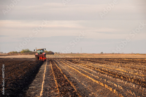 The tractor is working in the field, preparing the soil in the fall after harvesting the corn