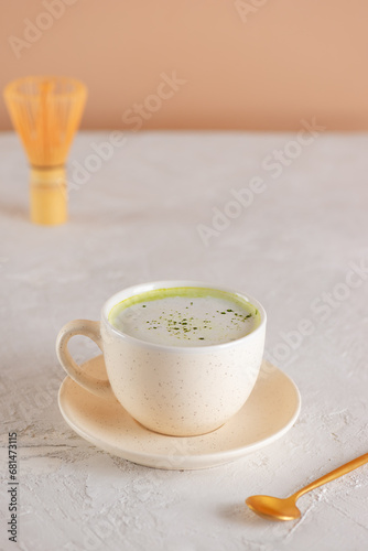 Green matcha latte drink with coconut milk in a cup and chasen on a table. Healthy drink, lactose, gluten and sugar free.