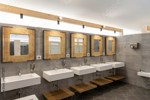 Public bathroom with five sinks, mirrors and soap dispensers. Modern and simple photo