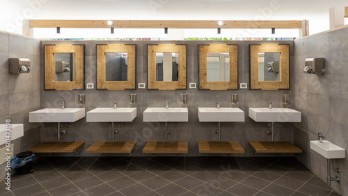 Public bathroom with five sinks, mirrors and soap dispensers. Modern and simple. photo