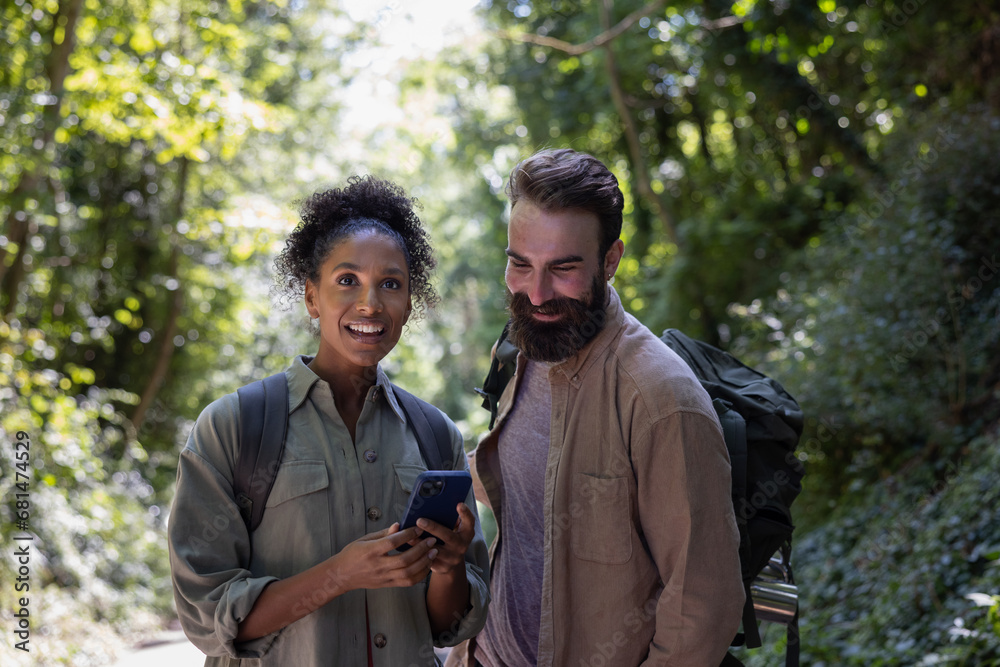 Couple enjoying hike through a forest using a smartphone to navigate Couple enjoying hike through a forest using a smartphone to navigate