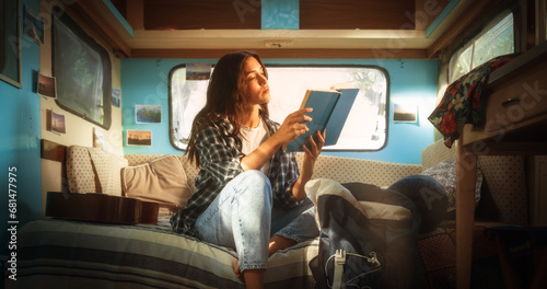 Young Adult Female Enjoying Her Time in a Motorhome, Relaxing and Reading an Adventure Book Story. Beautiful Girl Camping in a Caravan, Having a Journey to Rediscover Her True Self