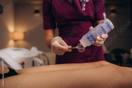 Master epilation applies hot wax gel for removal procedure hair in leg woman. Health and intimate hygiene concepts. Shugaring photo